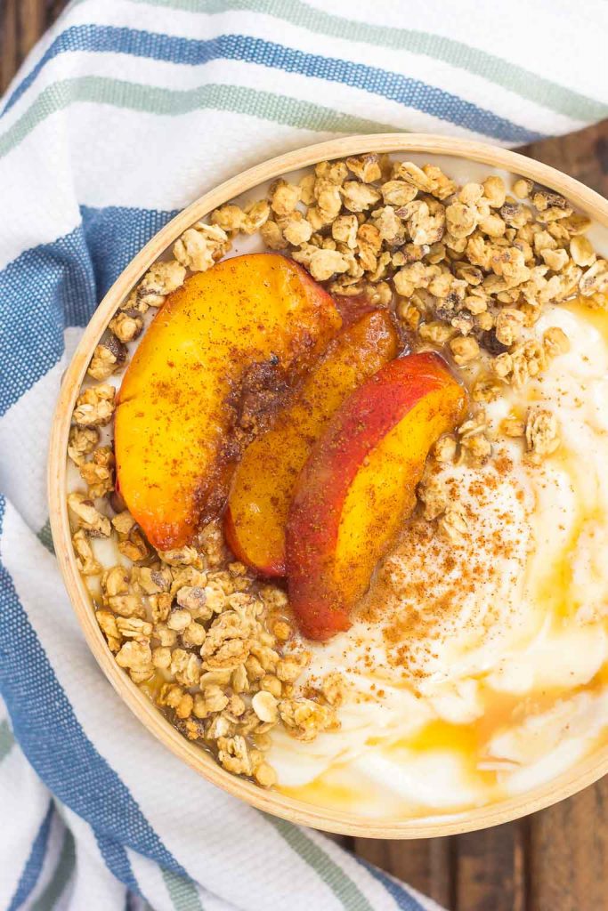 This Grilled Peach Caramel Yogurt Bowl is filled with creamy, vanilla Greek yogurt, grilled peaches with cinnamon and brown sugar, a sweet caramel sauce, and crunchy granola. It's ready in minutes and makes the perfect breakfast or snack!