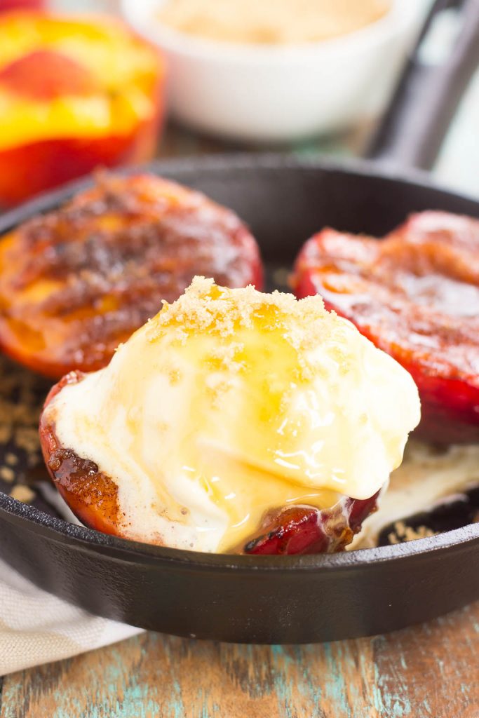 Three grilled peaches and ice cream in a cast iron skillet. 