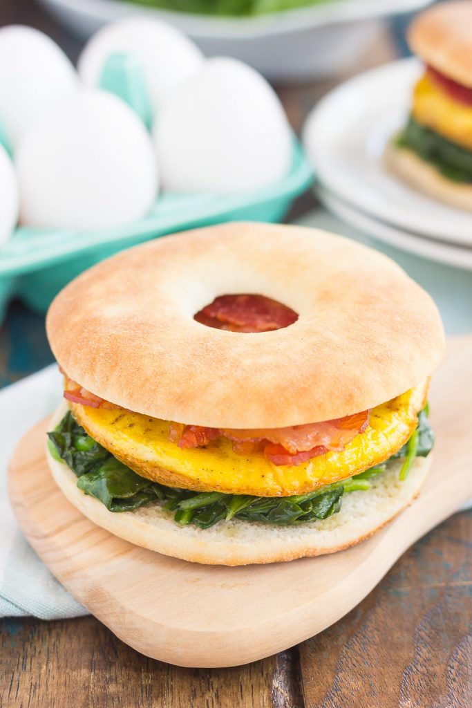 This Spinach, Bacon and Feta Breakfast Sandwich is an easy, make-ahead dish that's full of fresh ingredients. Fluffy eggs are seasoned with creamy feta cheese, and then topped sautéed spinach and smoky bacon. This sandwich makes a delicious and hearty breakfast for those busy weekday mornings! #sandwich #breakfastsandwich #bagelsandwich #eggbaconsandwich #eggsandwich #breakfast