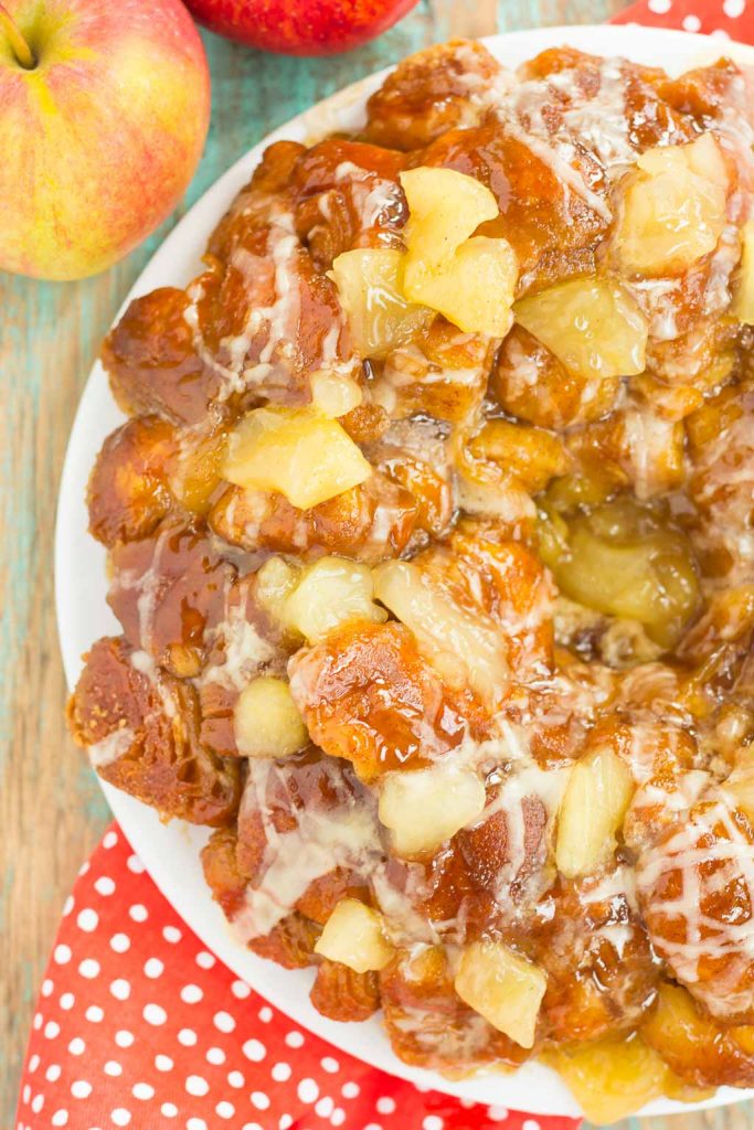 overhead view of apple monkey bread on a white plate. two apples stand nearby 