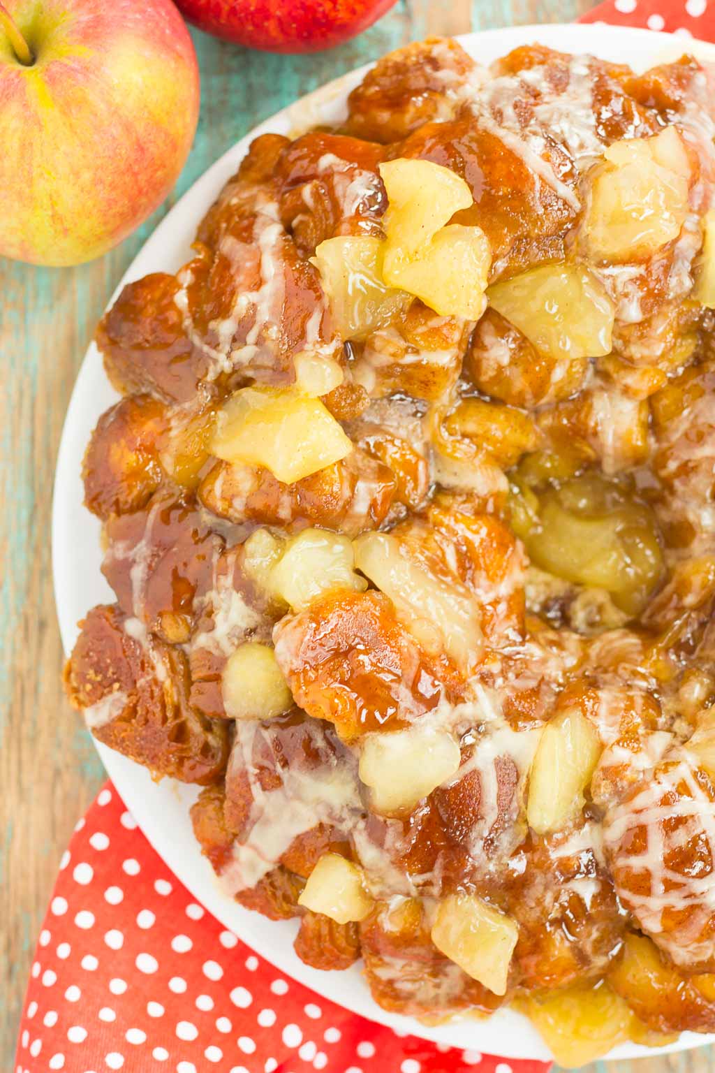 overhead view of apple monkey bread on a white plate. two apples stand nearby