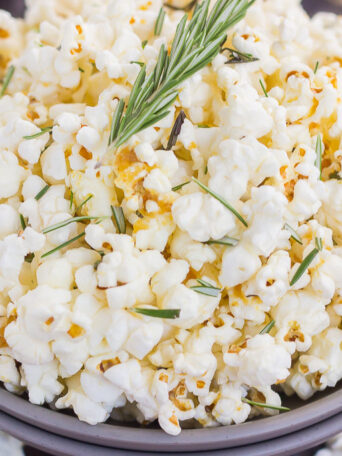 This Rosemary Garlic Popcorn is drizzled with a buttery mix filled with fresh rosemary and a hint of garlic. Simple, easy, and perfect for on-the-go entertaining, this crunchy snack is sure to be the hit of any party!