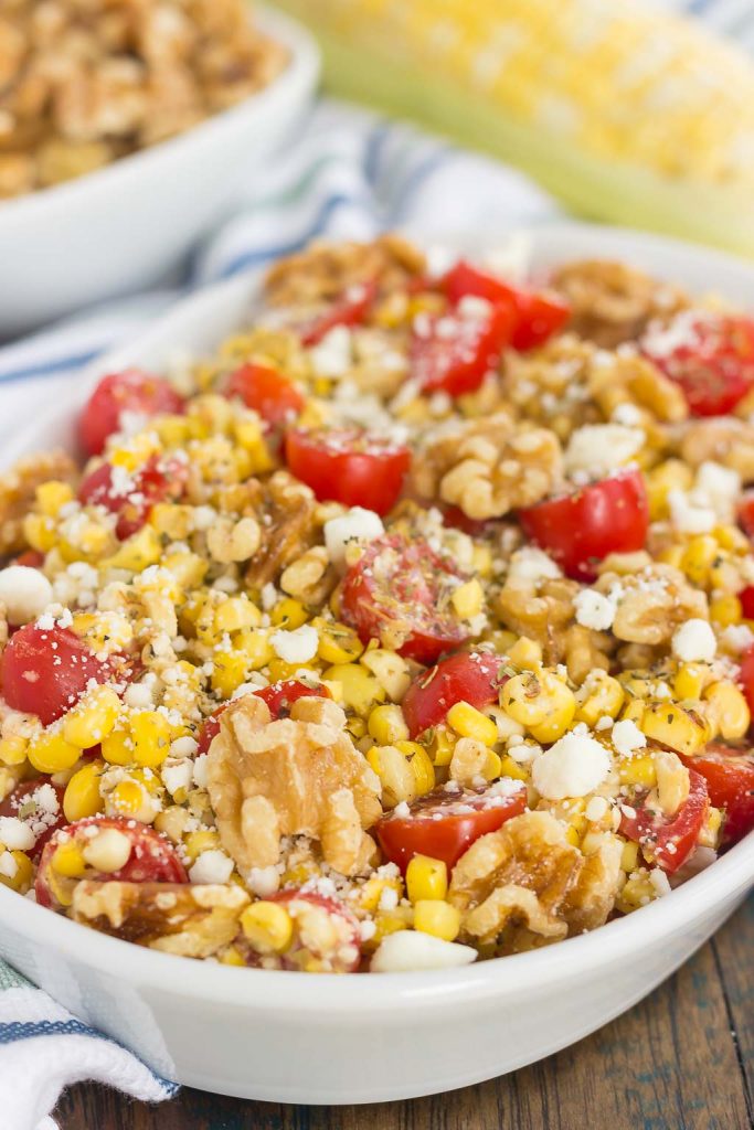 A large white serving platter of corn tomato feta salad. 