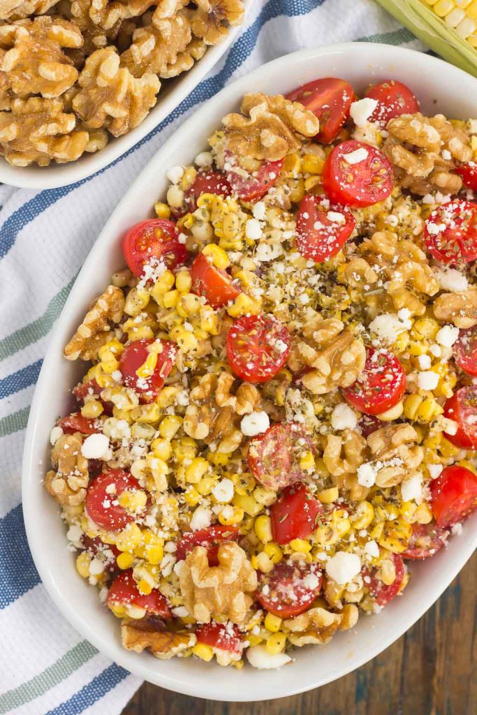 Overhead view of corn tomato feta salad in a white serving bowl. 