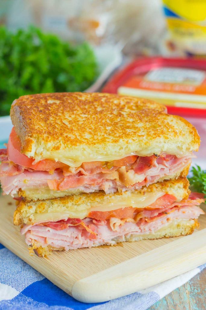 a grilled ham and swiss sandwich sliced in half and stacked on a cutting board