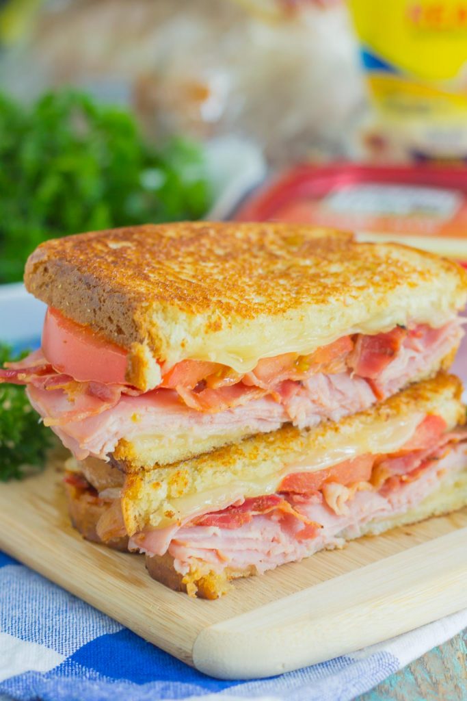 a grilled ham and cheese sandwich sliced in half and stacked on a cutting board