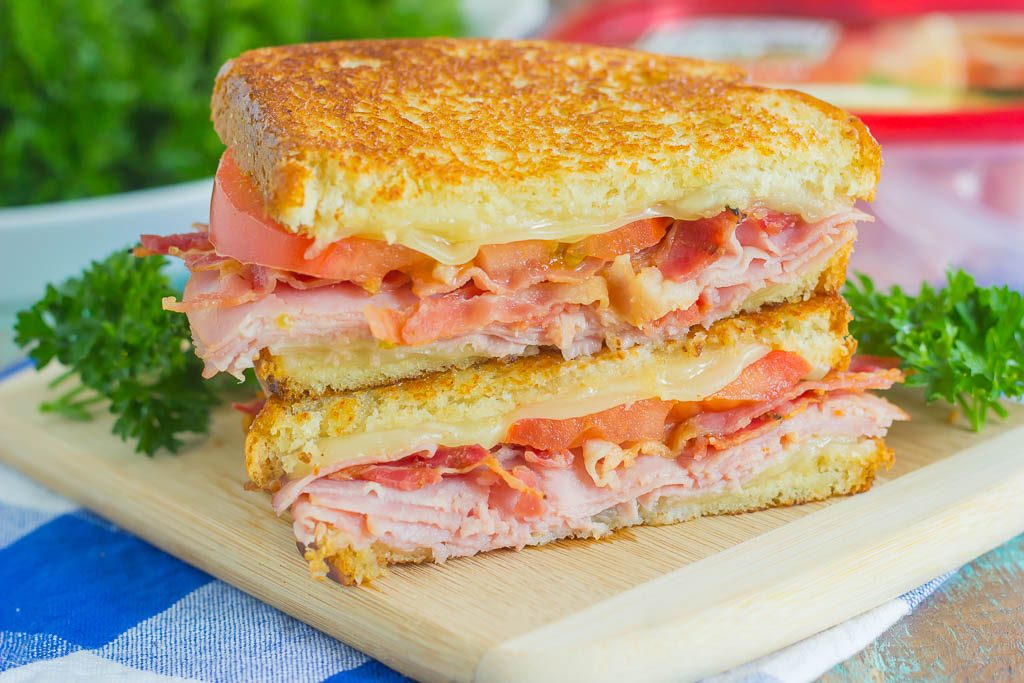 a grilled ham and swiss sandwich sliced in half and stacked on a cutting board