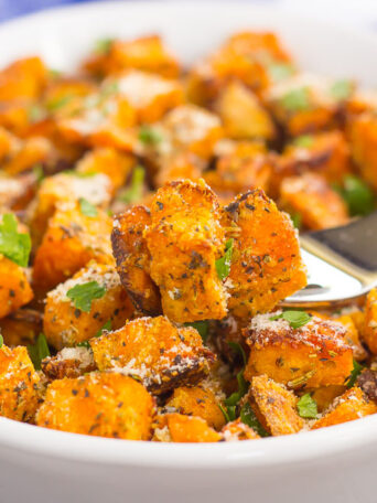 sweet potatoes in a white dish with a forkful showing a bite