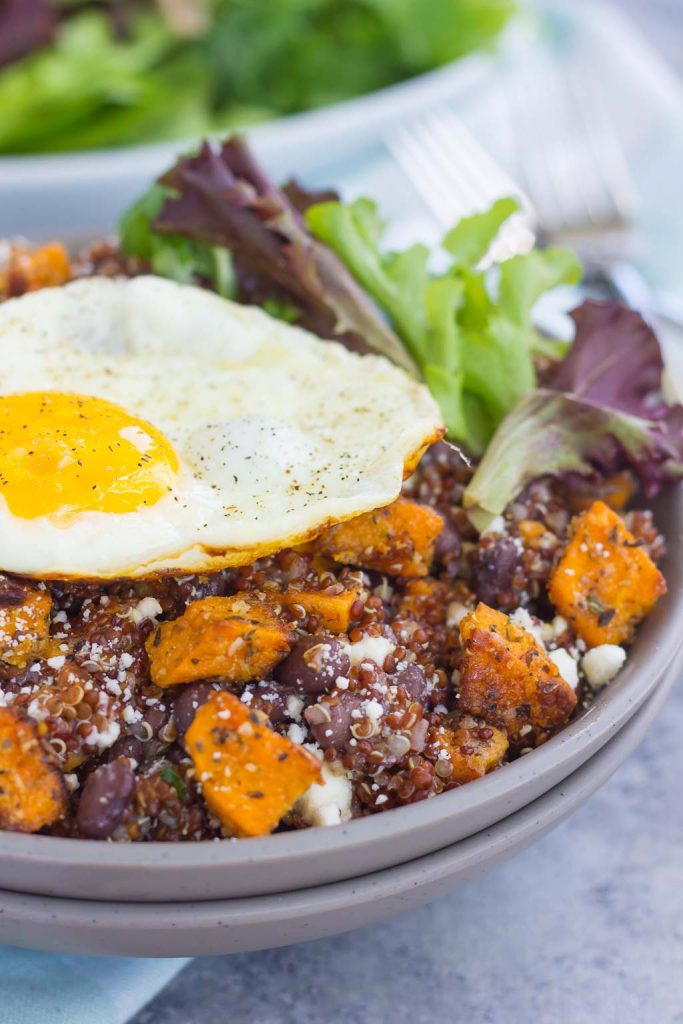This Roasted Parmesan Sweet Potato Quinoa Bowl is a deliciously simple dish that is perfect for a light lunch or dinner. Filled with roasted sweet potatoes, hearty quinoa, black beans, feta cheese, and a fried egg, this bowl is jam-packed with flavor and so easy to make! #sweetpotatoes #sweetpotatorecipe #quinoabowl #quinoabowlrecipes #falldish #fallrecipes #fallbreakfasts #fallbreakfastideas #breakfast #breakfastrecipes #recipe