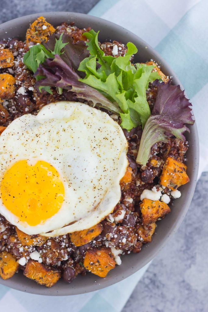 This Roasted Parmesan Sweet Potato Quinoa Bowl is a deliciously simple dish that is perfect for a light lunch or dinner. Filled with roasted sweet potatoes, hearty quinoa, black beans, feta cheese, and a fried egg, this bowl is jam-packed with flavor and so easy to make! #sweetpotatoes #sweetpotatorecipe #quinoabowl #quinoabowlrecipes #falldish #fallrecipes #fallbreakfasts #fallbreakfastideas #breakfast #breakfastrecipes #recipe