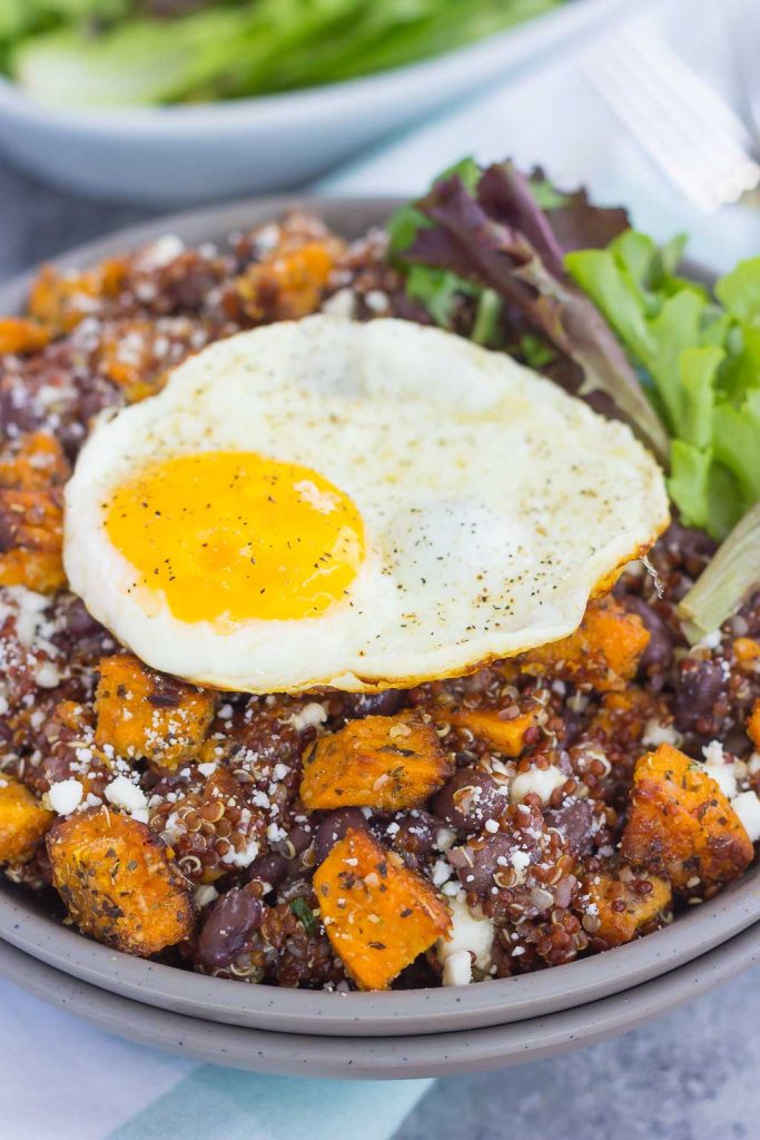 This Roasted Parmesan Sweet Potato Quinoa Bowl is a deliciously simple dish that is perfect for a light lunch or dinner. Filled with roasted sweet potatoes, hearty quinoa, black beans, feta cheese, and a fried egg, this bowl is jam-packed with flavor and so easy to make! #sweetpotatoes #sweetpotatorecipe #quinoabowl #quinoabowlrecipes #falldish #fallrecipes #fallbreakfasts #fallbreakfastideas #breakfast #breakfastrecipes #recipe