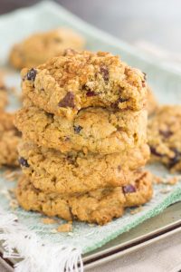 A stack of oatmeal cranberry chocolate chip cookies. The top cookie has a bite missing. 