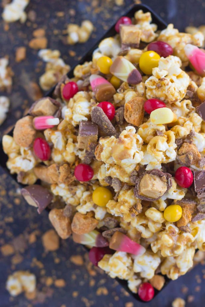 This Peanut Butter Candy Popcorn is the perfect sweet and salty snack to satisfy your sweet tooth! Fresh popcorn is coated with a creamy peanut butter mixture and then tossed with a variety of candies. It makes the best snack to munch on during Halloween, and is also a great way to use up that leftover candy!
