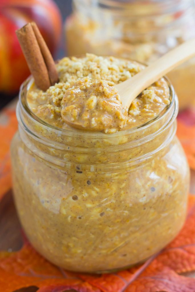 pumpkin overnight oats in a glass jar with a wooden spoon resting on top