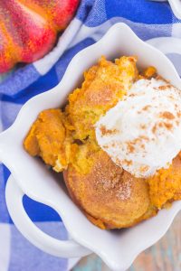 top down view of pumpkin cobbler in a white baking dish on a blue tablecloth