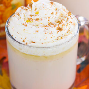 side view of white hot chocolate with caramel sauce and whipped cream in a mug