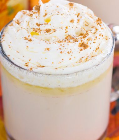 side view of white hot chocolate with caramel sauce and whipped cream in a mug