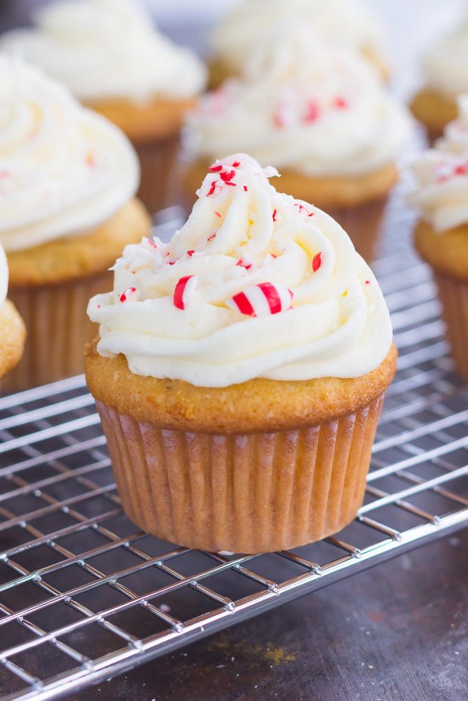 homemade vanilla cupcakes topped with a swirl of peppermint frosting on a cooling rack