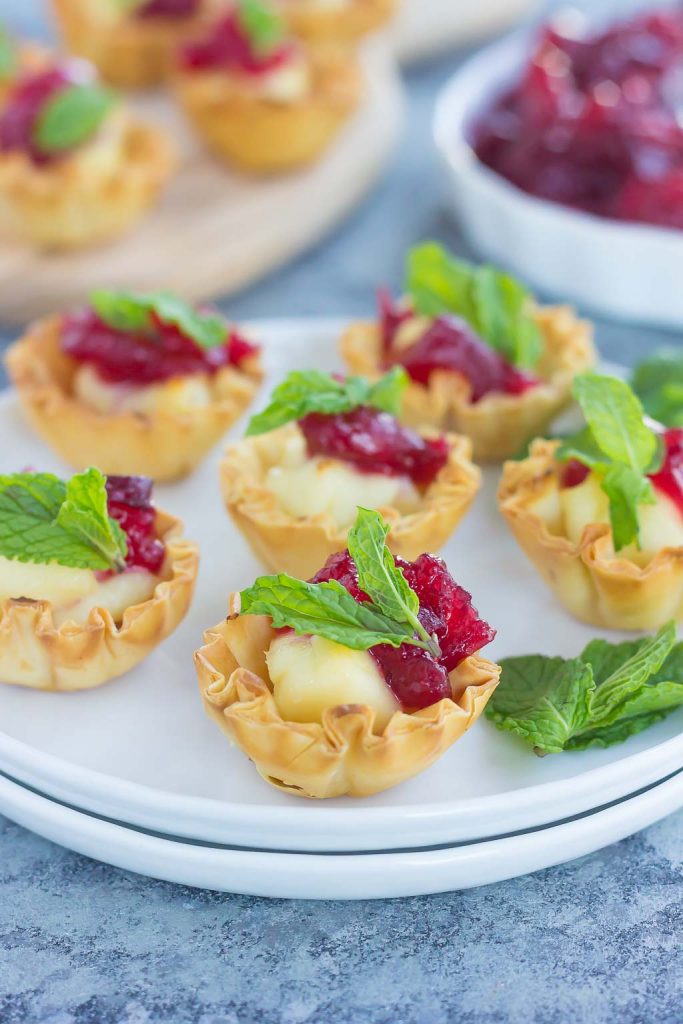 Cranberry brie bites on a stack of white plates. 