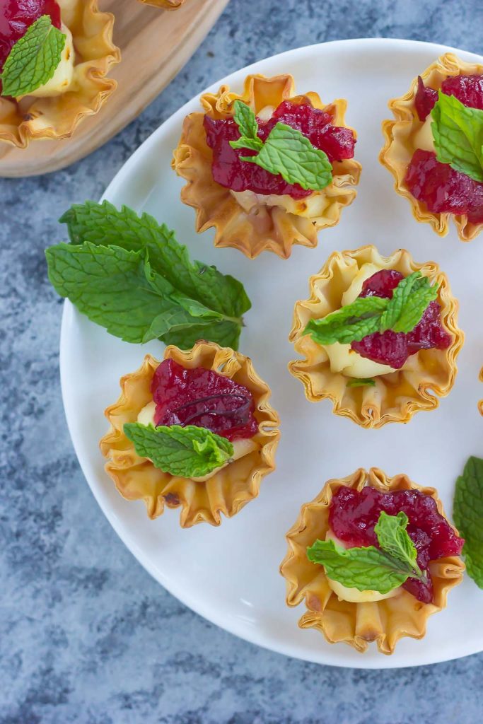 Overhead view of cranberry and brie bites on a white plate. 