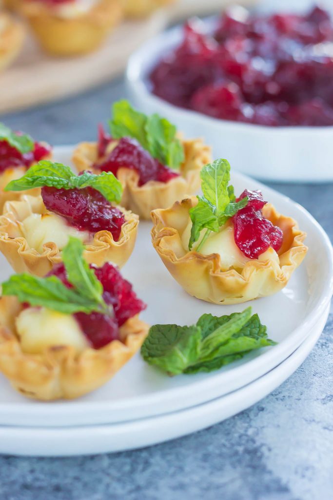 Cranberry brie bites on a stack of white plates. 