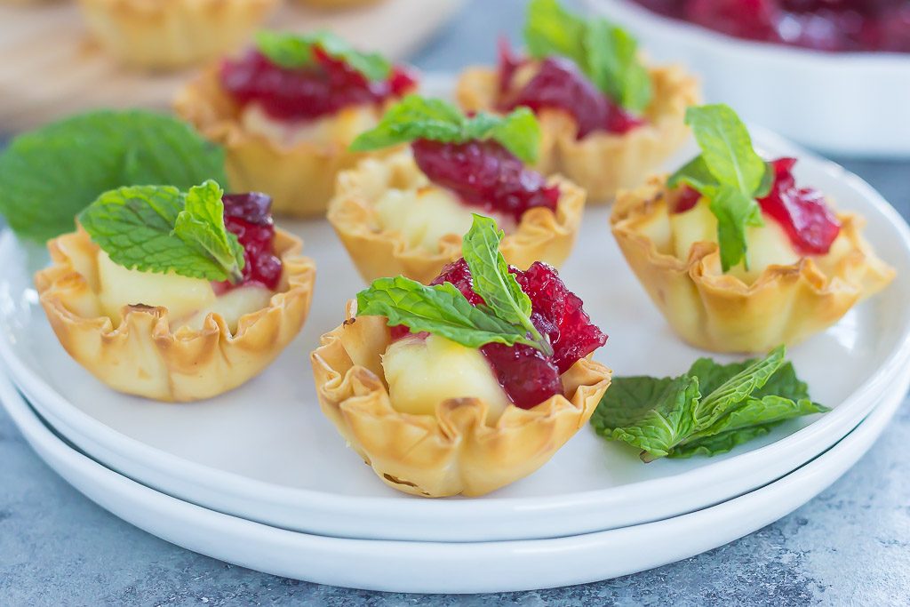 Cranberry brie bites on a stack of white plates. 