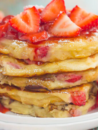 These Strawberry Greek Yogurt Pancakes are thick, fluffy, and loaded with juicy strawberries in every bite. Made with Greek yogurt for a healthier twist and topped with an easy strawberry sauce, you're going to fall in love with the sweet taste of these pancakes!