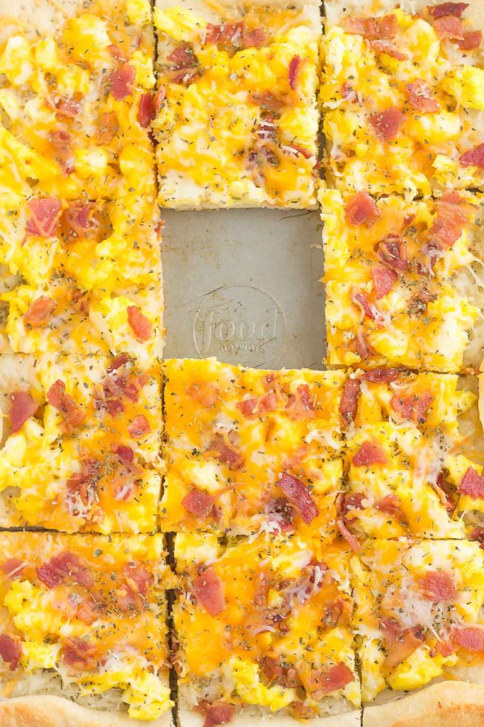 Overhead view of a sliced scrambled egg breakfast pizza with one square missing. 