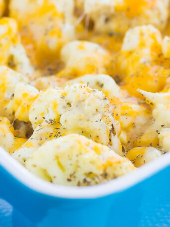 This Baked Cheesy Cauliflower is delicious way to jazz up your favorite veggie. Cauliflower florets are drizzled with olive oil, a blend of seasonings, and topped with two kinds of cheese. Baked until tender and oozing with flavor, this easy vegetable will quickly become a new mealtime favorite!