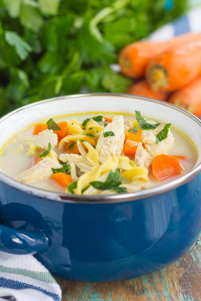 A bowl of slow cooker chicken noodle soup, garnished with fresh parsley. 