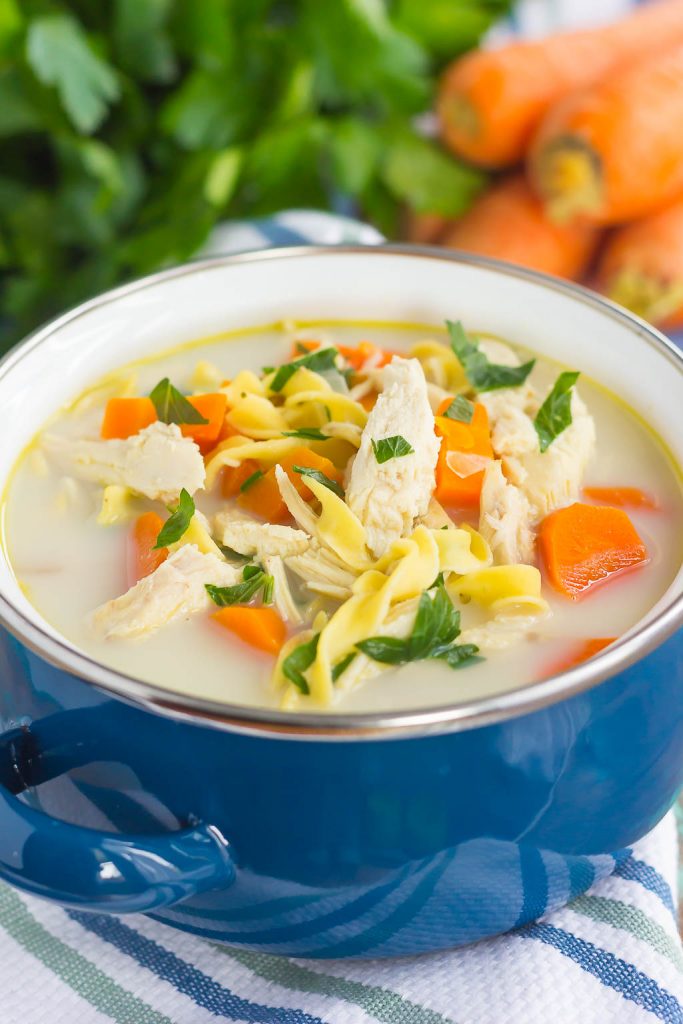 A blue bowl full of Crockpot creamy chicken noodle soup. 