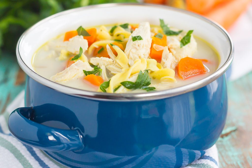 A blue bowl of homemade creamy chicken noodle soup. 