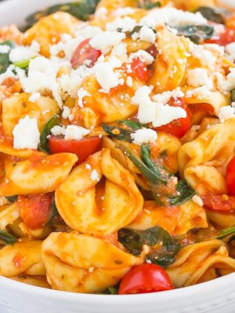 This Spinach and Feta Tortellini is fresh, flavorful, and ready in less than 30 minutes. Cheese tortellini is tossed in a zesty marinara sauce and sprinkled with fresh spinach and crumbled feta cheese. Easy to make and perfect for busy weeknights, this warm and comforting pasta will fill you up and keep you coming back for more!