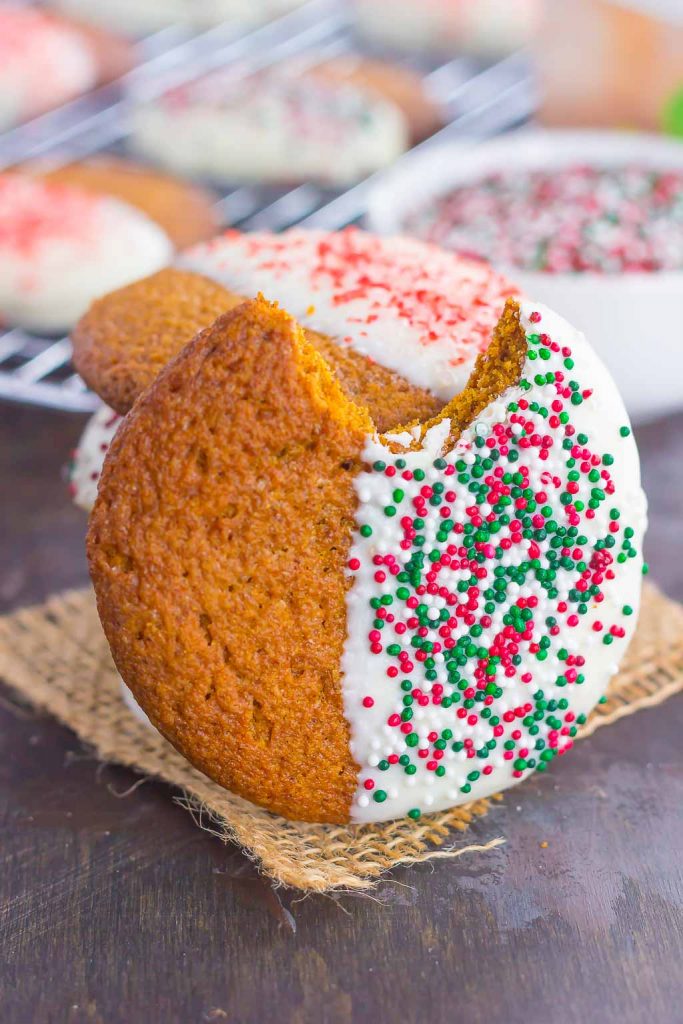 A soft and chewy gingersnap cookie resting on its side. A bite is missing and it's been dipped in white chocolate. 