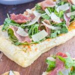 This Arugula and Prosciutto Puff Pastry Pizza is easy to make and ready in about 20 minutes. Puff pastry dough is drizzled with olive oil, and then topped with mozzarella cheese, fresh arugula, salty prosciutto and some shaved Parmesan cheese. Simple, fresh, and bursting with flavor, this lighter pizza is perfect for busy weeknights and is sure to be a mealtime winner