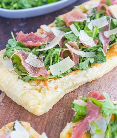 This Arugula and Prosciutto Puff Pastry Pizza is easy to make and ready in about 20 minutes. Puff pastry dough is drizzled with olive oil, and then topped with mozzarella cheese, fresh arugula, salty prosciutto and some shaved Parmesan cheese. Simple, fresh, and bursting with flavor, this lighter pizza is perfect for busy weeknights and is sure to be a mealtime winner
