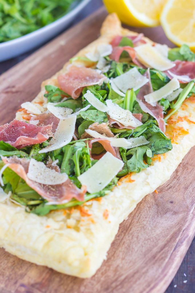 This Arugula and Prosciutto Puff Pastry Pizza is easy to make and ready in about 20 minutes. Puff pastry dough is drizzled with olive oil, and then topped with mozzarella cheese, fresh arugula, salty prosciutto and some shaved Parmesan cheese. Simple, fresh, and bursting with flavor, this lighter pizza is perfect for busy weeknights and is sure to be a mealtime winner