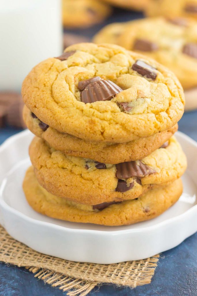 A stack of chocolate chip cookies with Reese's peanut butter cups on a white plate. 