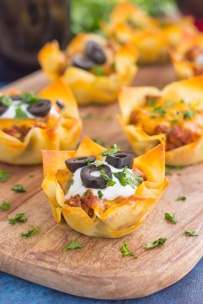 Baked wonton taco cups on a wooden serving board. 