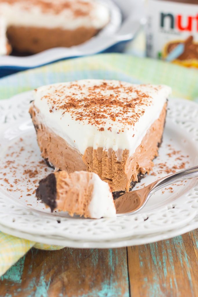 front view of a slice of no bake chocolate pie on a white plate with a fork. 