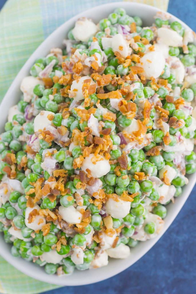 overhead shot of pea salad with bacon in white serving dish