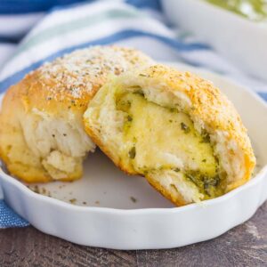 These Stuffed Cheesy Pesto Rolls are an easy dish to make for those hungry dinner guests. Soft and buttery rolls are filled with pesto sauce and mozzarella cheese, and then baked until golden. Crispy on the outsize and oozing with flavor on the inside, this simple roll is sure to wow even the pickiest of eaters!