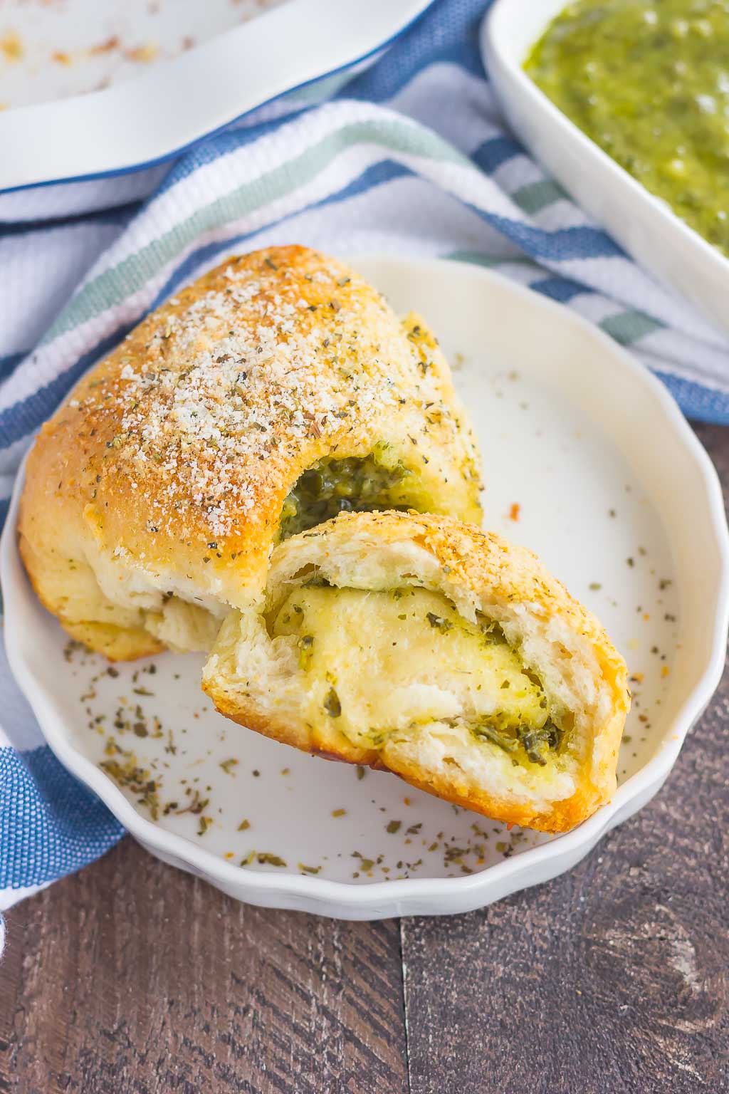 These Stuffed Cheesy Pesto Rolls are an easy dish to make for those hungry dinner guests. Soft and buttery rolls are filled with pesto sauce and mozzarella cheese, and then baked until golden. Crispy on the outsize and oozing with flavor on the inside, this simple roll is sure to wow even the pickiest of eaters!