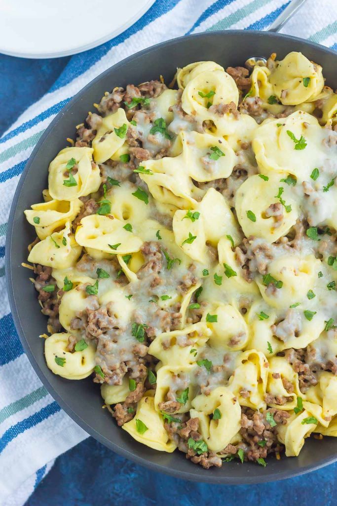 overhead view of a ground beef tortellini skillet topped with melted cheese 