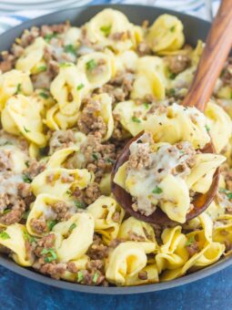 pasta in a black skillet with a wooden spoon showing a spoonful