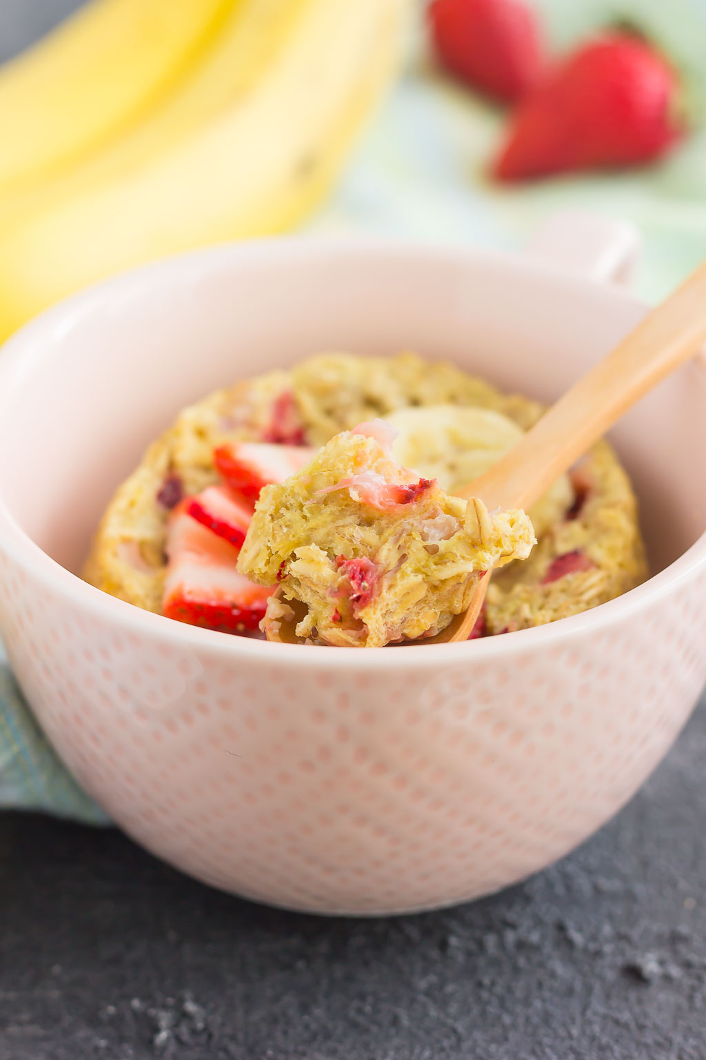single serve baked oatmeal in a pink bowl, with a wooden spoon.