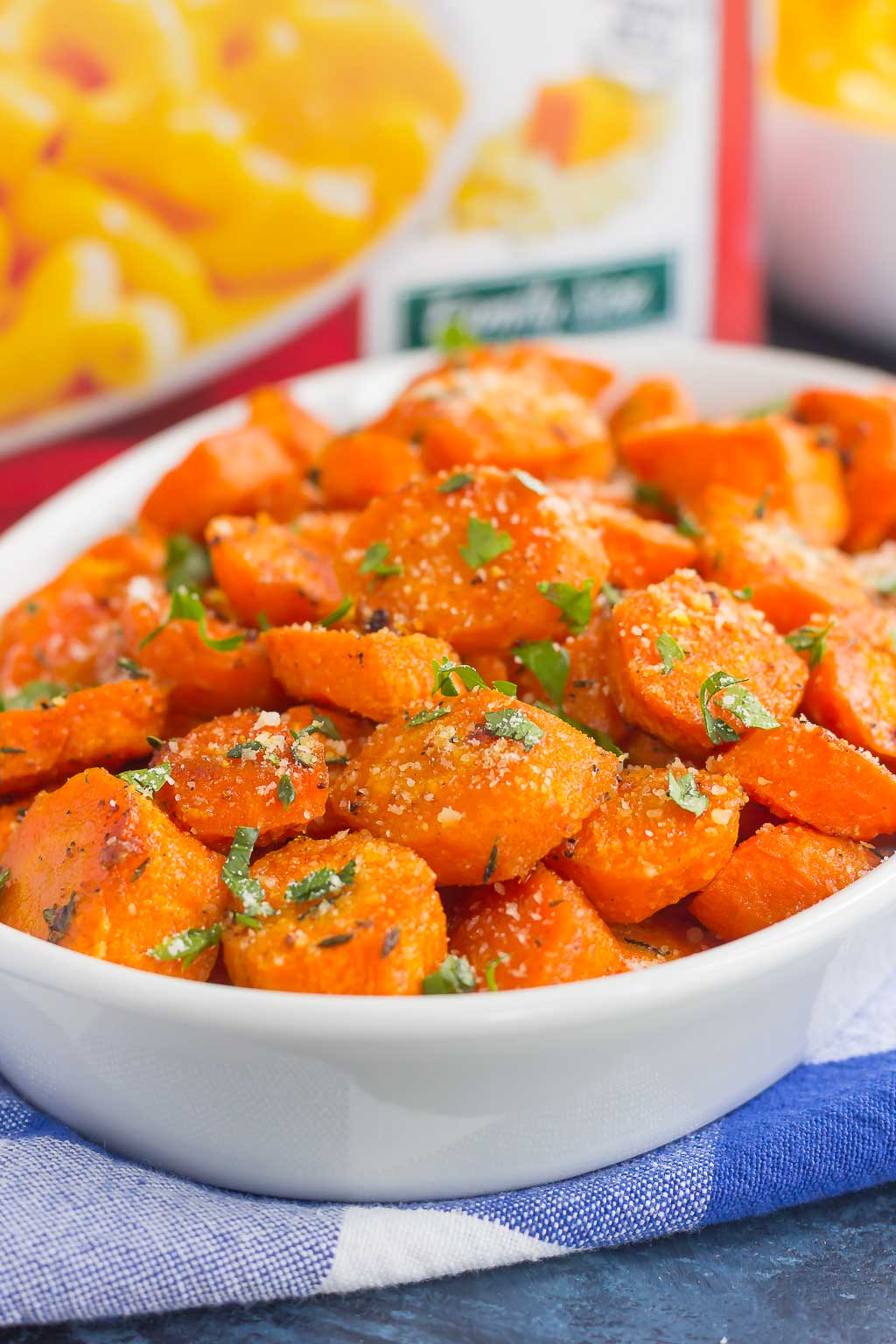 A dish of honey roasted carrots. A box of mac and cheese rests in the background. 