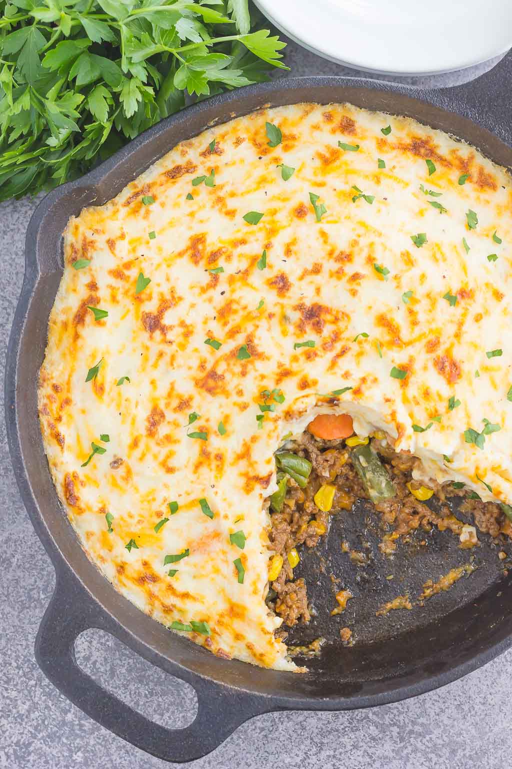 overhead view of simple shepherd's pie in a cast iron skillet. a portion is missing. 