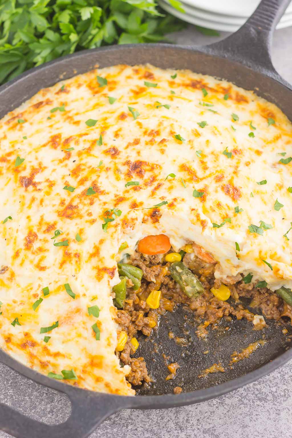 a quick shepherd's pie with cheese in a cast iron skillet, a portion is missing. 