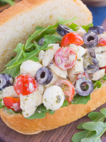 This Italian Chicken Salad is fresh, easy, and bursting with flavor. Loaded with mozzarella cheese, tomatoes, black olives and pesto, this fun twist on a classic flavor will have you coming back for more. This salad is perfect for an easy lunch or dinner and makes delicious sandwiches, too!